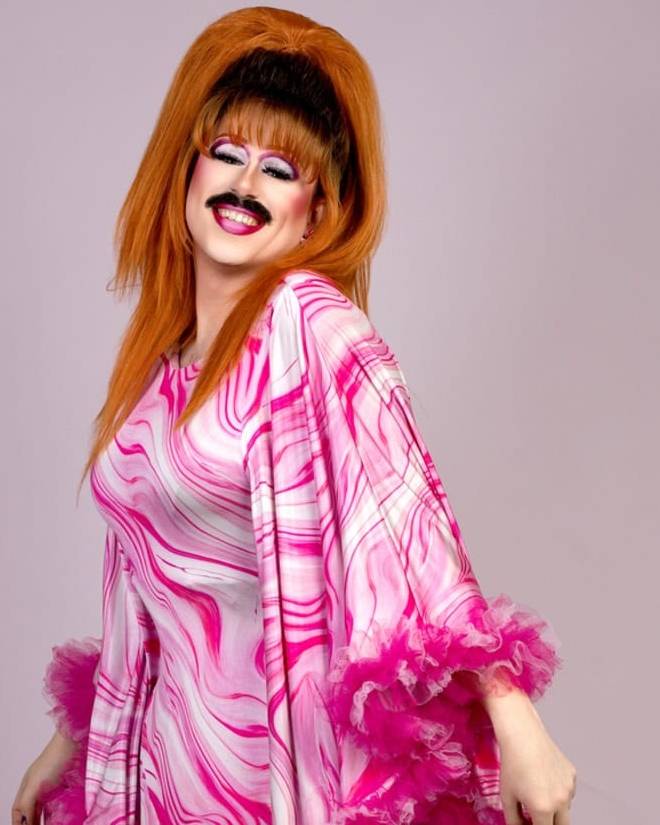 Flick in a pink marbled gown with a ginger beehive and curly moustache